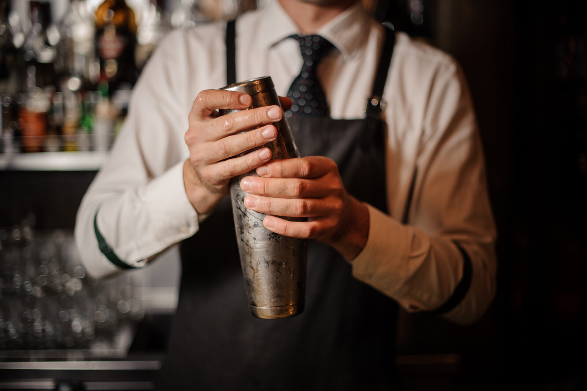 A man in an apron holding a cocktail shaker.